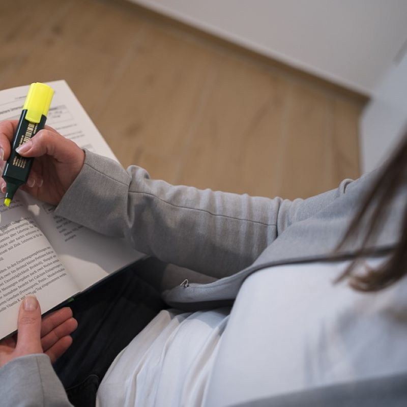 Bettina Augustin, Inhaberin der Nährstoffpraxis, markiert für eine Gesundheitsberatung mit einem Textmarker in einem Buch